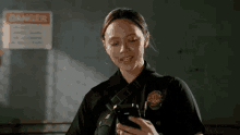 a police officer is looking at her cell phone in front of a danger sign .