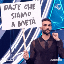 a man holding a sign that says " daje che siamo a meta "