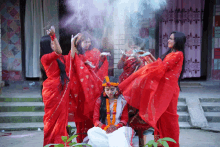 a woman in a white dress is surrounded by other women in red