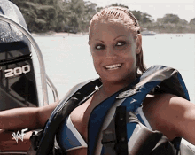 a woman wearing a life jacket is standing in front of a boat with the number 200 on the side