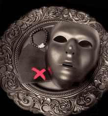 a silver plate with a mask and a bracelet with a red x on it