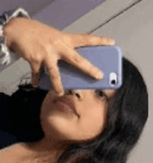 a woman is taking a selfie with her hand on her phone .