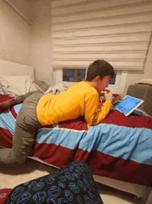 a boy in a yellow shirt is laying on a bed