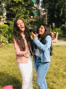 two girls are posing for a picture in a park