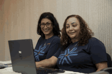 two women are looking at a dell laptop and smiling