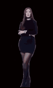 a woman in a black dress and black stockings stands in front of a black background