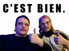 two men give a thumbs up in front of a sign that says c ' est bien