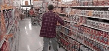 a man in a plaid shirt is walking down a grocery store aisle with a sign that says frozen dinners