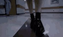 a woman wearing black boots is walking down a hallway in a hospital .