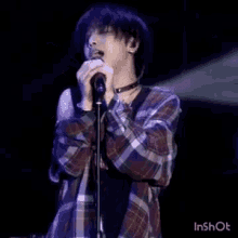 a man in a plaid shirt is singing into a microphone .