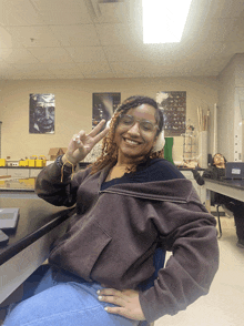 a woman wearing goggles giving a peace sign in a lab