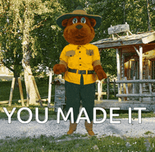 a teddy bear in a sheriff 's uniform stands in front of a cabin that says " you made it "