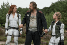 a man with a tattoo on his chest is standing next to two women