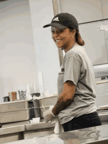 a woman wearing a black adidas hat smiles in a kitchen