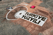 a group of people standing on top of a hill with turkeye yüzyili written on the ground