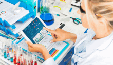 a woman in a lab coat is looking at a tablet with graphs on it