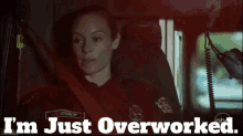 a woman is sitting in an ambulance with the words i 'm just overworked below her