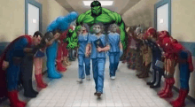 the hulk is walking down a hallway with a group of superheros .