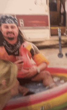 a man is sitting in a pool with a flamingo float on his head .