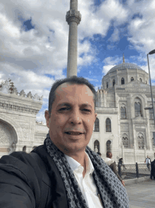 a man takes a selfie in front of a large building