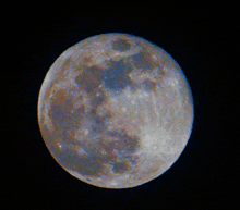 a full moon against a black background with a few spots on it