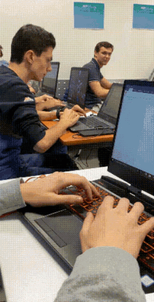 a group of people are typing on laptops in front of a wall that has a sign that says ' microsoft '