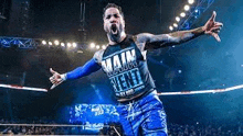 a wrestler is standing in a wrestling ring with his arms outstretched in front of a crowd .