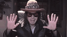 a man wearing a cowboy hat and sunglasses is making a funny face .