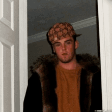 a young man wearing a hat and a fur coat stands in a doorway