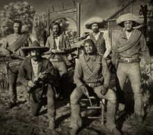 a black and white photo of a group of cowboys with guns