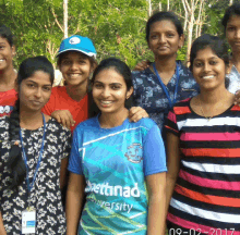 a group of young women posing for a photo with one wearing a shirt that says ' settinad university ' on it