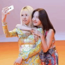 two women are taking a selfie together with their cell phones .