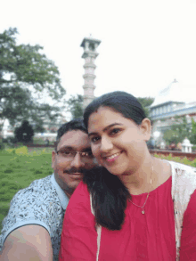 a man and a woman are posing for a picture in front of a tower