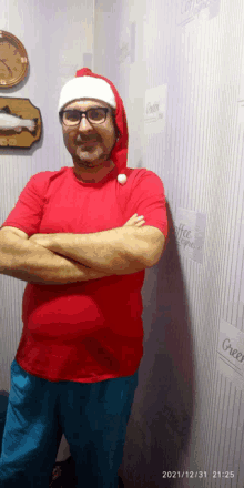 a man wearing a santa hat stands with his arms crossed in front of a wall with coffee express written on it