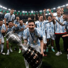 a soccer player is holding a trophy in front of a group of players .