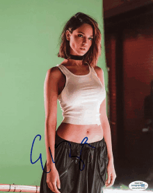 a woman in a white tank top and black pants has a signature on her photo