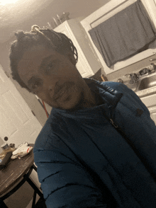 a man wearing a blue north face jacket takes a selfie in a kitchen