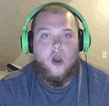 a man with a beard wearing green headphones looks surprised