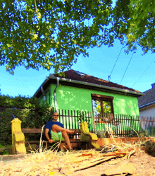 a man sits on a bench outside a green house