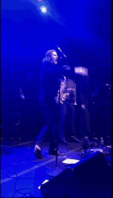 a man singing into a microphone on a stage with blue lights behind him