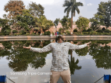 a man stands in front of a lake with his arms outstretched and the words " samsung triple camera mah " below him