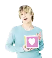 a man in a blue sweater is holding a pink square with a heart on it