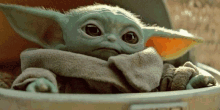 a close up of a baby yoda from star wars sitting in a trash can .