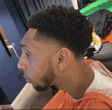 a man with curly hair and a beard is getting his hair cut by a barber