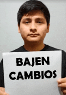 a man is holding a sign that says ' bajen cambios '