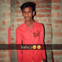 a young man wearing a red shirt with a picture of a skull on the front and the words " sahu ji " on the bottom