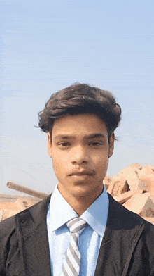 a young man wearing a blue shirt and tie stands in front of a pile of bricks with the letters tmc on them