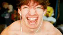 a shirtless man wearing ear buds making a funny face