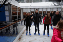 a group of people are ice skating on a rink with a man wearing a jacket that says john deere on it