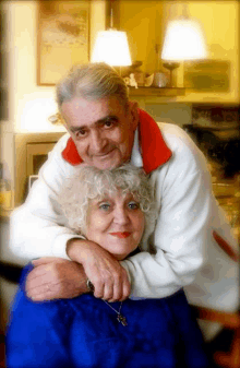 a man and woman are posing for a picture and the man is wearing a white sweater with a red collar